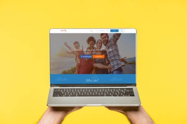 couchsurfing Web sitesi ile dizüstü bilgisayar ekranında sarı izole tutan kişi kırpılmış atış
