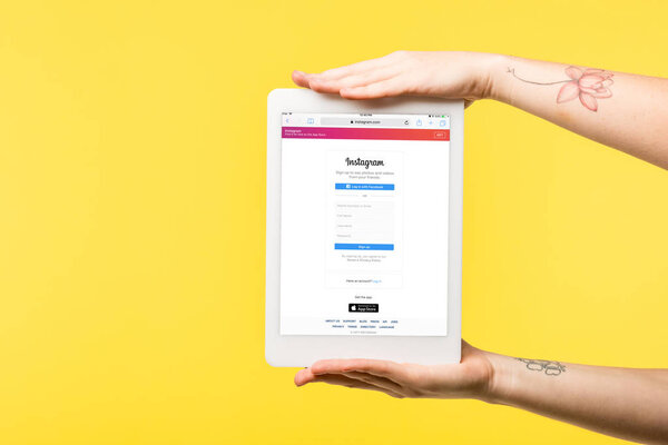 cropped shot of person holding digital tablet with instagram app on screen isolated on yellow  