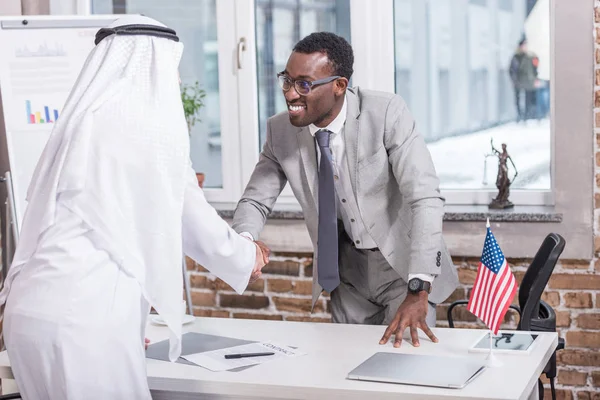 アフリカ系アメリカ人のビジネスマンがオフィスでアラビア語のパートナーと握手 — ストック写真