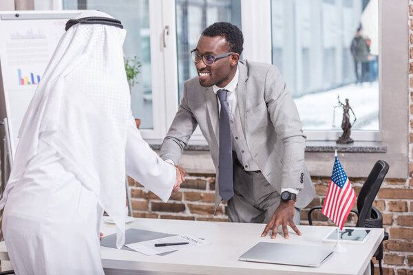 African american businessman shaking hands with arabic partner in office 