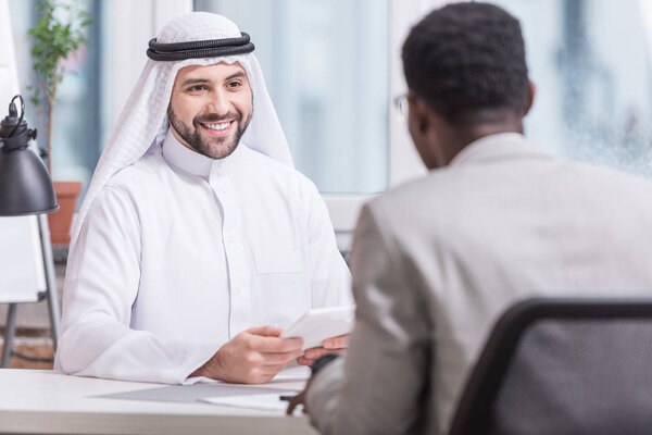 Arabian businessman smiling and holding digital tablet in office 