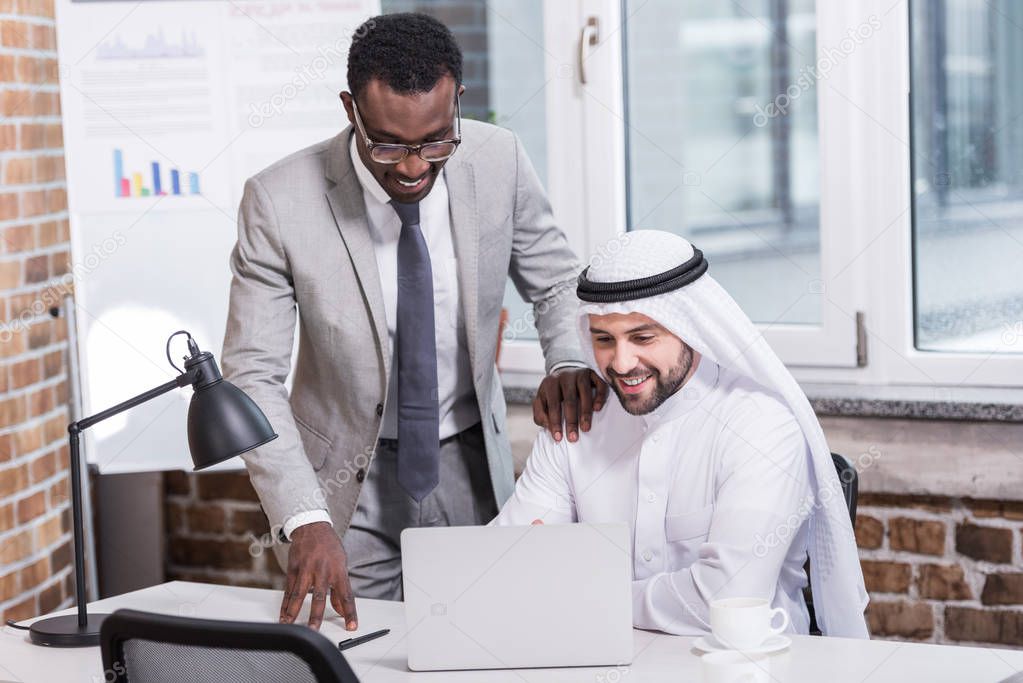 Multicultural businessmen looking at computer in modern office 