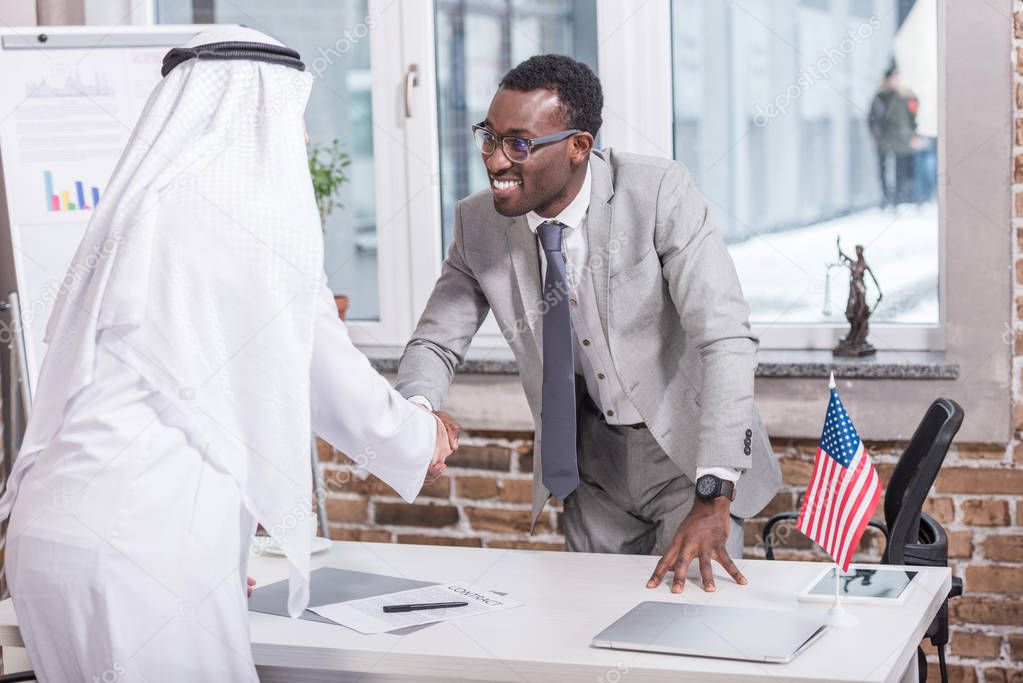 African american businessman shaking hands with arabic partner in office 