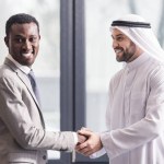 Close up view of african american businessman and arabic partner shaking hands in office