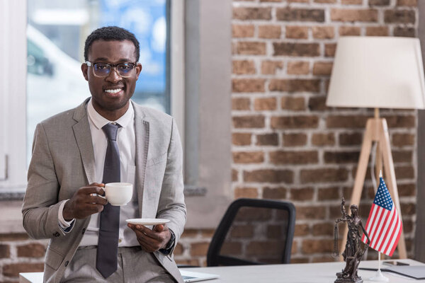 Африканский американский бизнесмен пьет кофе в офисе
 
