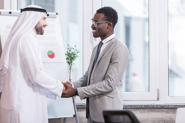 Businessmen smiling and shaking hands in modern office
