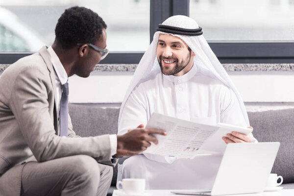 Multicultural businessmen talking and smiling in modern office 