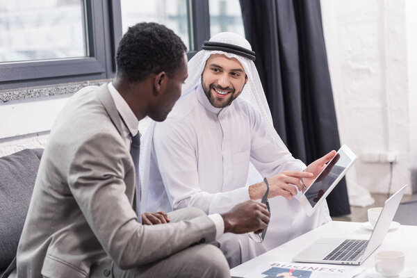 Arabian businessman smiling and using digital device in modern office