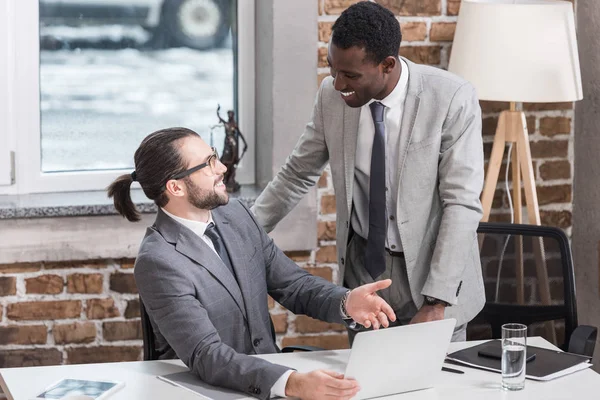 Hombres Negocios Multiétnicos Sonriendo Mirándose Hablando Oficina — Foto de stock gratis