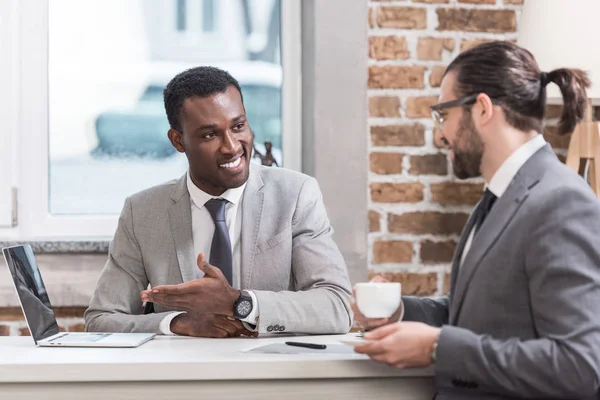 Smiling Multiethnic Businessmen Drinking Coffee Having Discussion Office Table Laptop — Stock Photo, Image