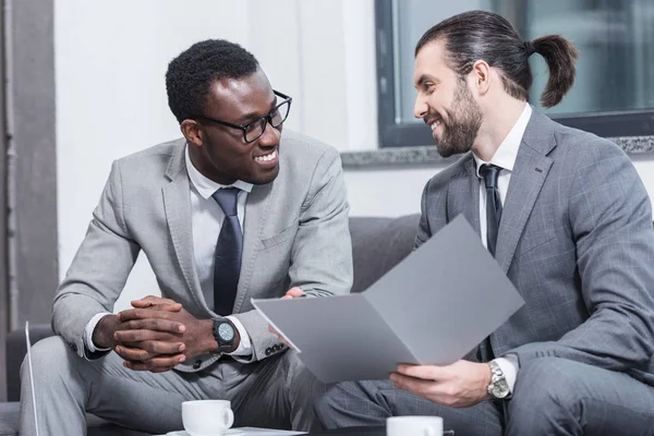 Sonrientes Socios Negocios Multiétnicos Sentados Sofá Hablando Oficina — Foto de Stock