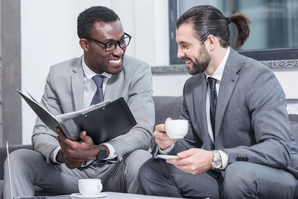 Successful Multiethnic Businessmen Sitting Couch Smiling Drinking Coffee Office — Free Stock Photo