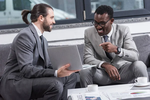 Smiling African American Businessman Sitting Couch Pointing Finger Business Partners — Free Stock Photo