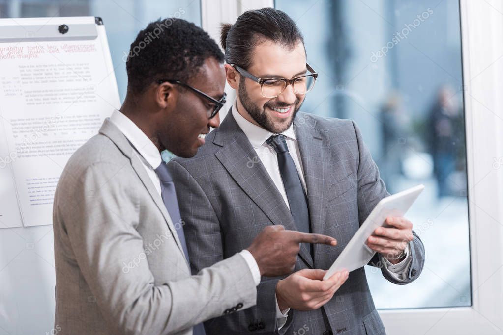 multiethnic business partners looking at digital tablet in office