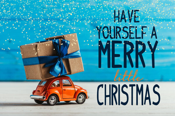 крупным планом игрушечный автомобиль с подарочной коробкой на синем деревянном фоне с вдохновением "Веселого Рождества"
