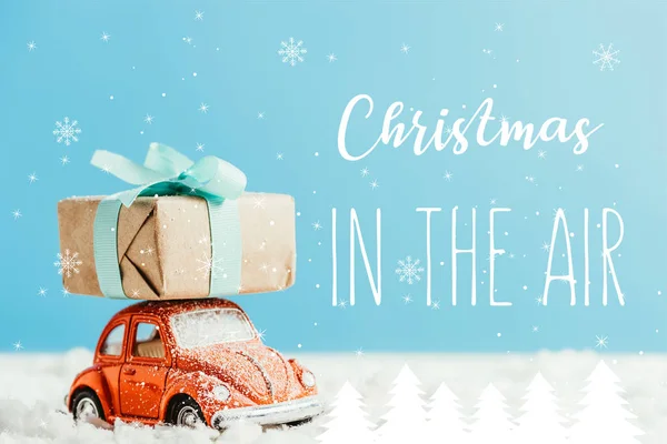 玩具红色汽车的特写镜头与圣诞节礼物乘坐由棉花制成的雪在蓝色背景与 圣诞节在空气中 的启发 — 图库照片