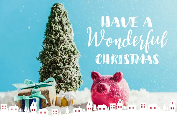 ミニチュア クリスマス ツリー ギフトと貯金とインスピレーションを 素晴らしいクリスマスを持っている と青の背景に雪の上に立って家の図 — ストック写真
