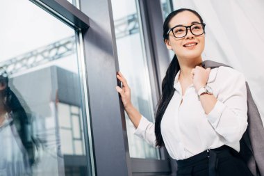 office penceresinde hazır omuz üzerinde ceket ile güzel iş kadını
