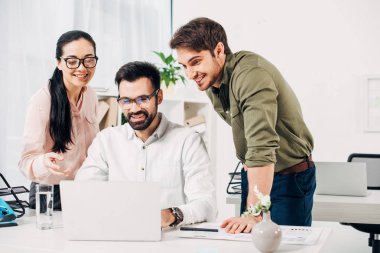 ofis içinde laptop bakarak gülümseyen office yöneticileri