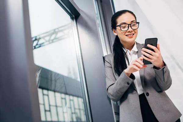 Smiling Businesswoman Standing Window Touching Smartphone Screen — Stock Photo, Image