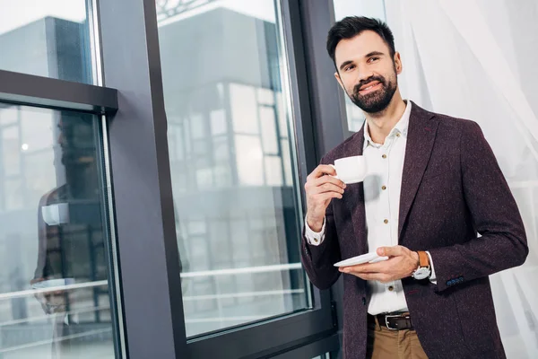 Stilig Affärsman Står Vid Fönstret Och Håller Kaffekopp — Gratis stockfoto