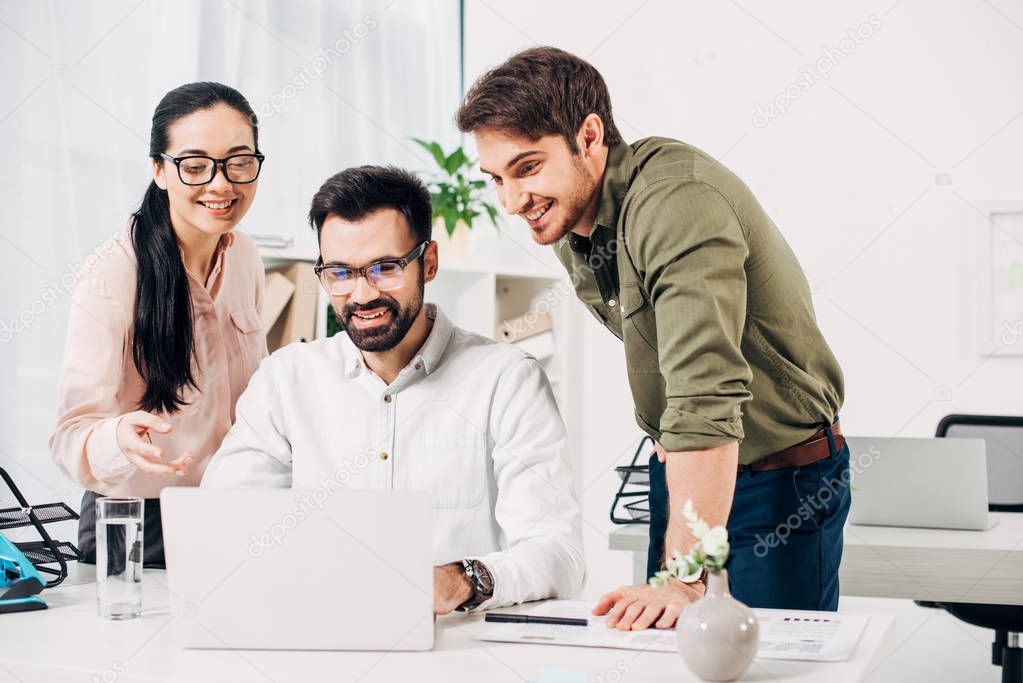 smiling office managers looking at laptop in office