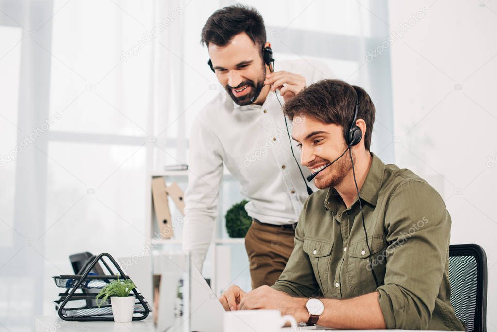 smiling call center operators looking at laptop screen in office