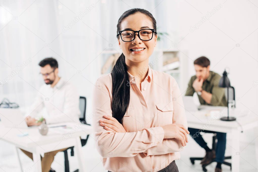 Smiling female manager standing with crossed arms in office 