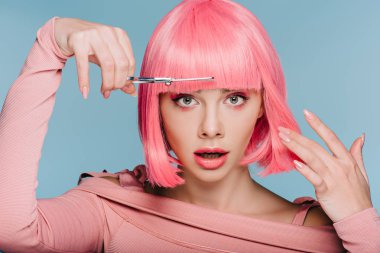 shocked stylish girl cutting pink hair with scissors isolated on blue clipart