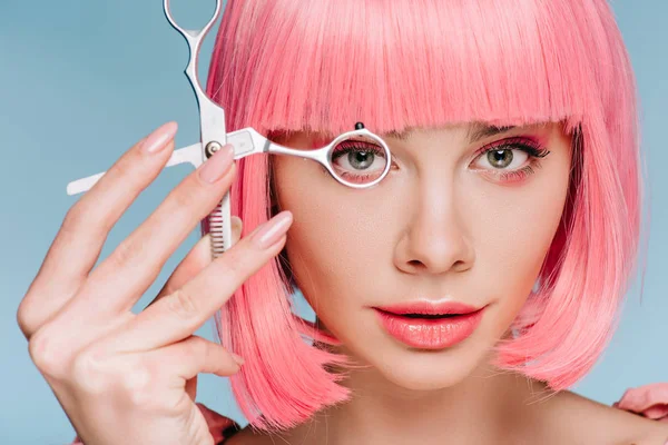 有吸引力的感性女孩与粉红色的发型看通过剪刀孤立在蓝色 — 图库照片