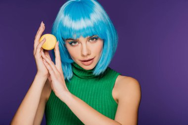 çekici kız mavi peruk üzerinde mor izole lezzetli macaron ile poz