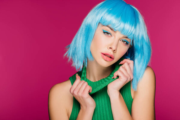 charming girl posing in blue wig and green turtleneck, isolated on pink