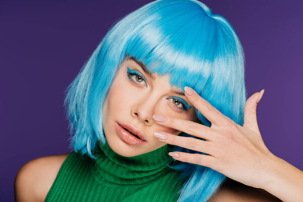 attractive young woman in blue wig showing nails with manicure, isolated on purple