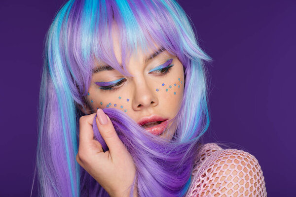 pretty girl posing in violet wig with stars on face, isolated on purple