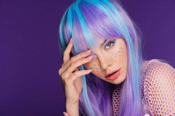 beautiful girl posing in violet wig with stars on face, isolated on purple