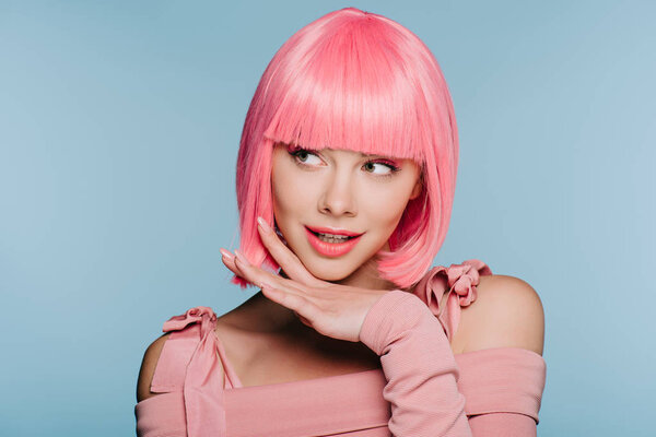 beautiful stylish girl smiling, gesturing and posing in pink wig isolated on blue