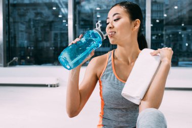 omuz içme suyu spor salonunda spor şişe üzerinde havlu ile çekici Asyalı kız