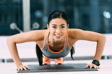 çekici Asya görünümünü yakın basın yapıyor kız ups fitness mat ve spor salonunda gülümseyen