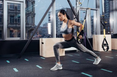attractive asian girl training with resistance bands at modern gym clipart