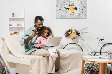 Afro-Amerikan aile oturma odasında dizüstü bilgisayar kullanarak