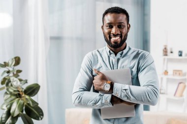 Afro-Amerikan freelancer eller içinde laptop ile gülümseyen