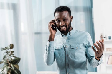 Afrika kökenli Amerikalı adam oturma odasında Smartphone cep telefonu ile konuşmak