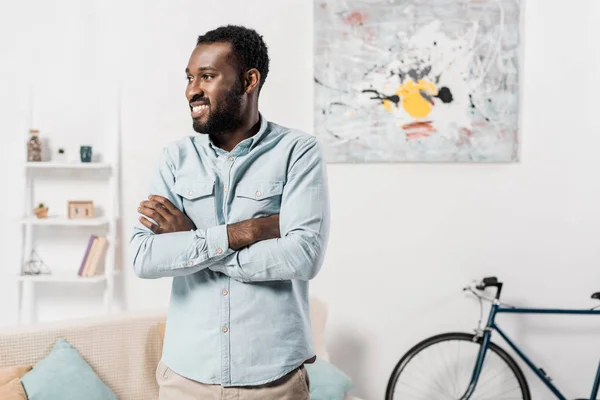 african american man standing with arms crossed in living room