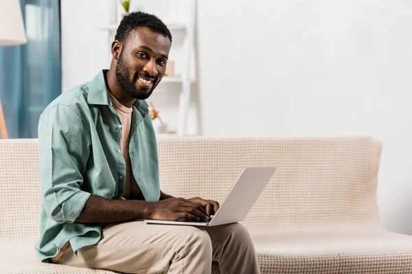 Афроамериканський Чоловік Використовує Ноутбук Колінах Дивиться Камеру Вітальні — стокове фото