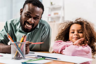 kalem tutan ve oturma odasında çizim ile kızı yardım Afrikalı-Amerikalı babası görünümünü kapat