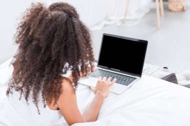 evde sabah zaman sırasında yatakta boş ekranlı dizüstü bilgisayar kullanan kıvırcık kız dikiz