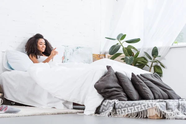 Selektiv Fokus För Afroamerikanska Ung Kvinna Använder Digitala Tablett Sängen — Gratis stockfoto