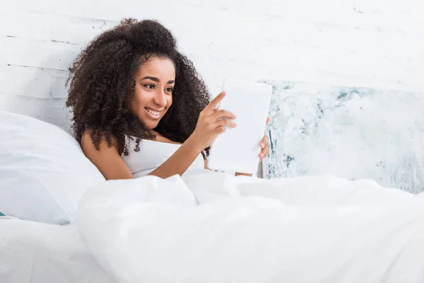 美丽的非洲裔美国妇女使用数字平板电脑在家里的床上 — 免费的图库照片