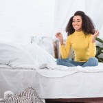 Стильная молодая африканская американка медитирует в позе лотоса дома Стильная молодая африканская американка медитирует в позе лотоса дома