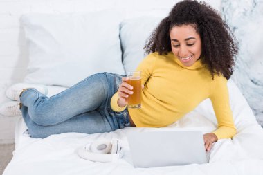 bardak taze meyve suyu laptop yatakta evde çalışma ile genç kadın serbest meslek